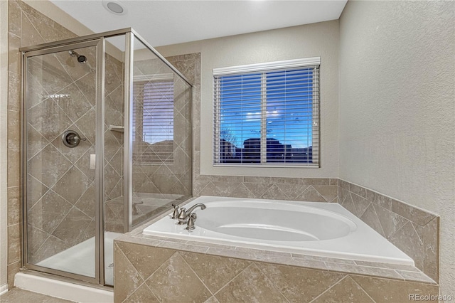 bathroom with a textured wall, a garden tub, and a shower stall