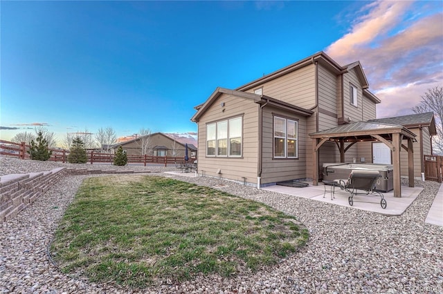 back of property with a fenced backyard, a patio, a lawn, a gazebo, and a hot tub