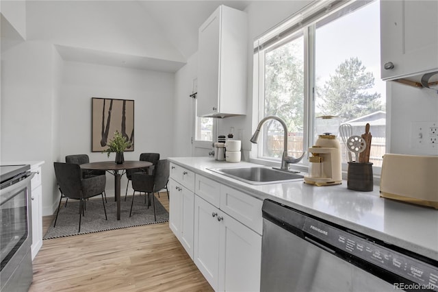 6579 Ingalls St, Arvada, CO 80003 - kitchen with stainless steel appliances, light wood-style floors, light countertops, white cabinetry, and vaulted ceiling