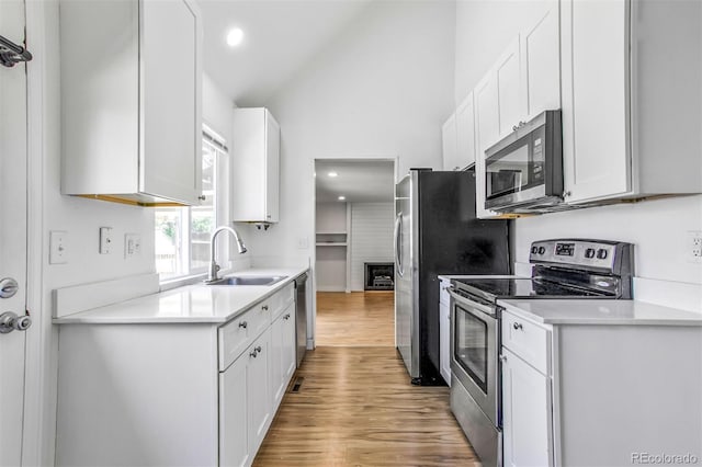 6579 Ingalls St, Arvada, CO 80003 - kitchen featuring appliances with stainless steel finishes, lofted ceiling, light wood-type flooring, white cabinets, and light countertops