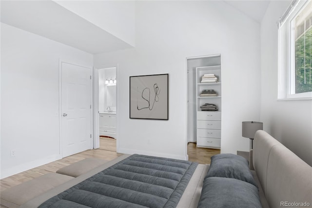 6579 Ingalls St, Arvada, CO 80003 - bedroom with light wood finished floors, a spacious closet, lofted ceiling, and ensuite bathroom