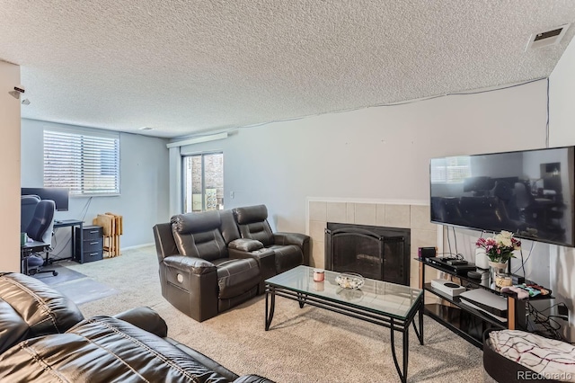 living room featuring carpet floors, a tile fireplace, and a textured ceiling