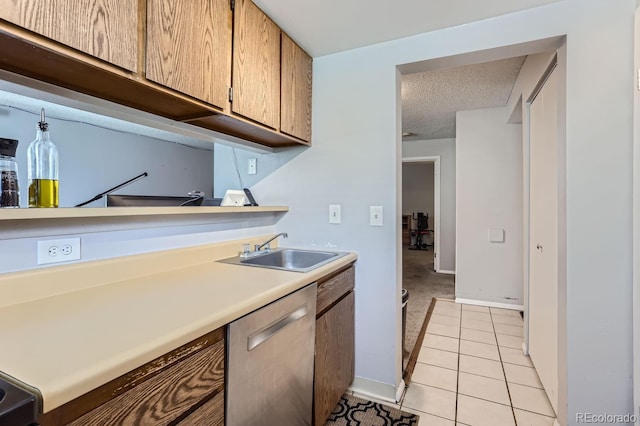 kitchen with light tile patterned flooring, stainless steel dishwasher, sink, and a textured ceiling