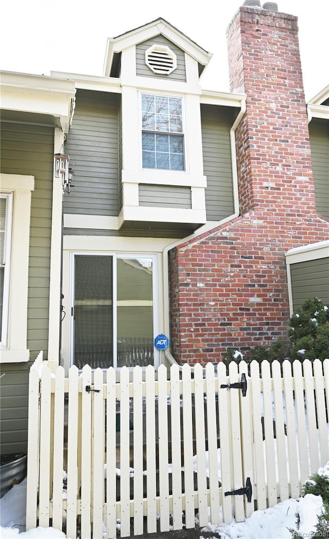 exterior space with brick siding, fence, and a chimney