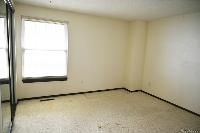 unfurnished room with a textured ceiling, visible vents, and baseboards