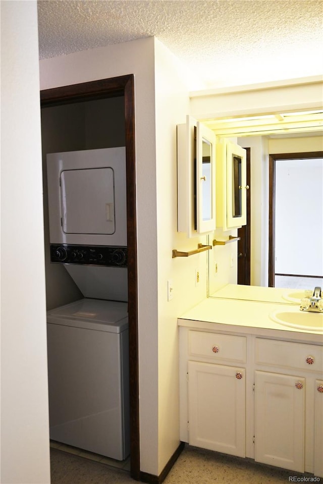 laundry room featuring stacked washer and clothes dryer, a sink, a textured ceiling, and laundry area