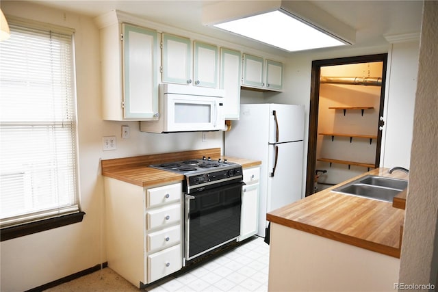 kitchen with wooden counters, white appliances, light floors, and a sink