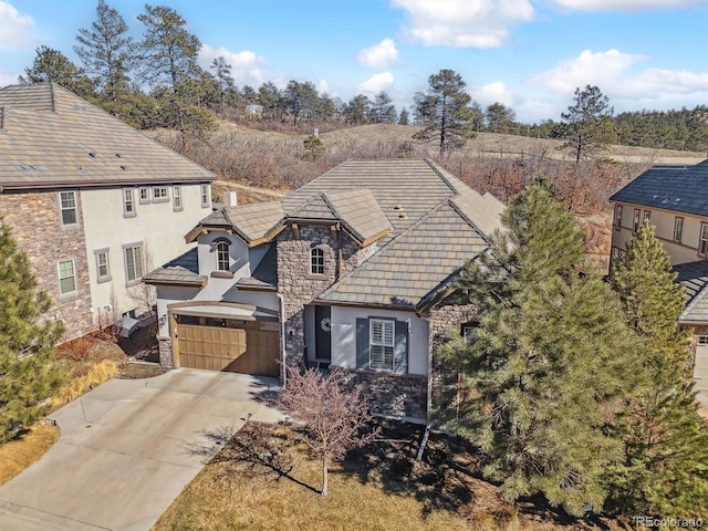 view of front of house featuring stone siding, concrete driveway, and stucco siding