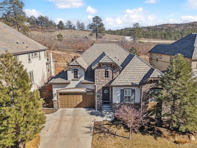 view of front of home with stone siding, concrete driveway, and stucco siding