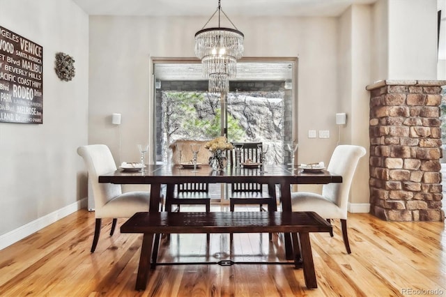 dining space with baseboards, a chandelier, and wood finished floors