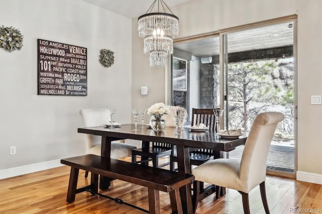 dining room featuring a notable chandelier, wood finished floors, and baseboards