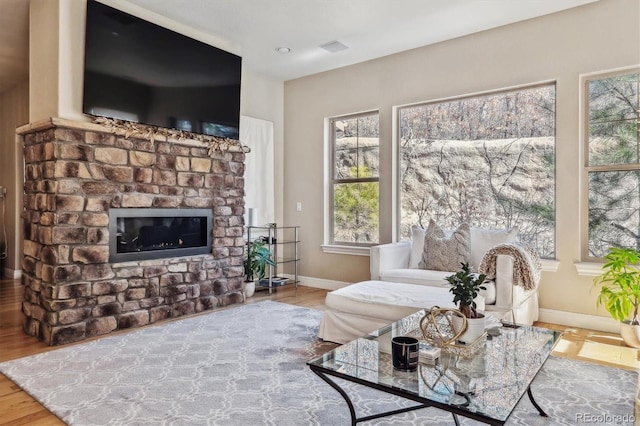 living area featuring a fireplace, wood finished floors, visible vents, and baseboards