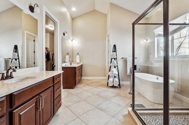 bathroom featuring vaulted ceiling, two vanities, a sink, and a freestanding bath