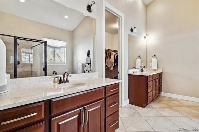 bathroom featuring vanity, baseboards, a spacious closet, tile patterned floors, and a stall shower