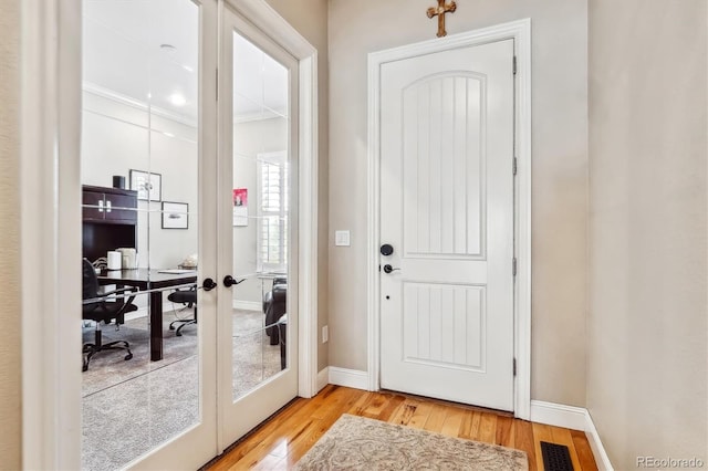 doorway featuring light wood-style floors, visible vents, baseboards, and french doors