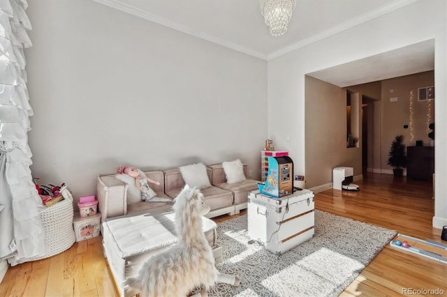 living area with ornamental molding, an inviting chandelier, wood finished floors, and baseboards