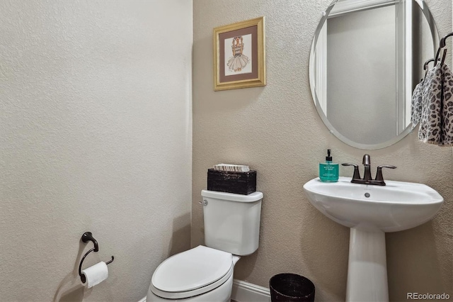 half bath featuring a textured wall and toilet