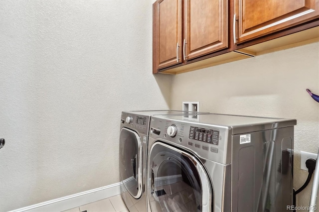 washroom featuring light tile patterned floors, independent washer and dryer, cabinet space, and baseboards