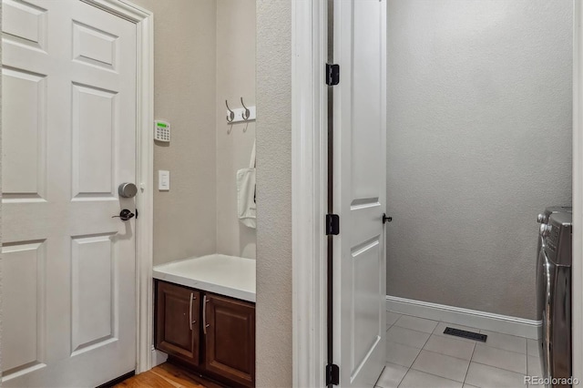 bathroom with baseboards, a textured wall, tile patterned flooring, and washer and dryer