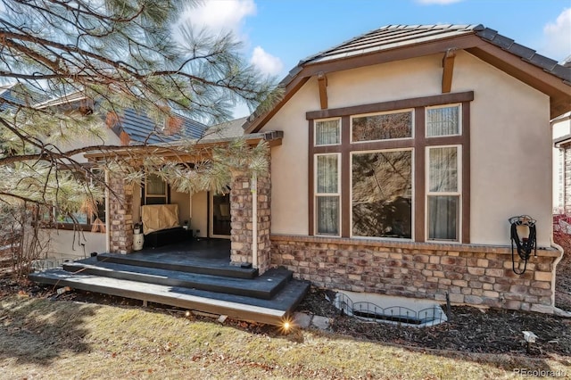 rear view of property with stone siding and stucco siding