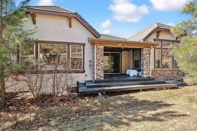 rear view of house with stone siding and stucco siding