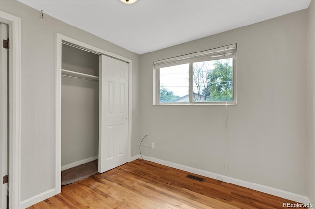 unfurnished bedroom featuring a closet, light wood-type flooring, visible vents, and baseboards