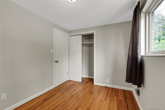 unfurnished bedroom featuring light wood-style floors, multiple windows, and baseboards