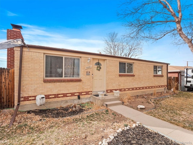 view of front of home with brick siding, fence, and a chimney