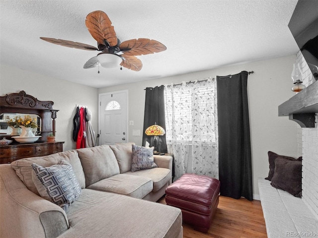 living area with ceiling fan, a textured ceiling, and wood finished floors