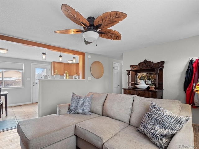 living area with light tile patterned floors, a ceiling fan, and baseboards