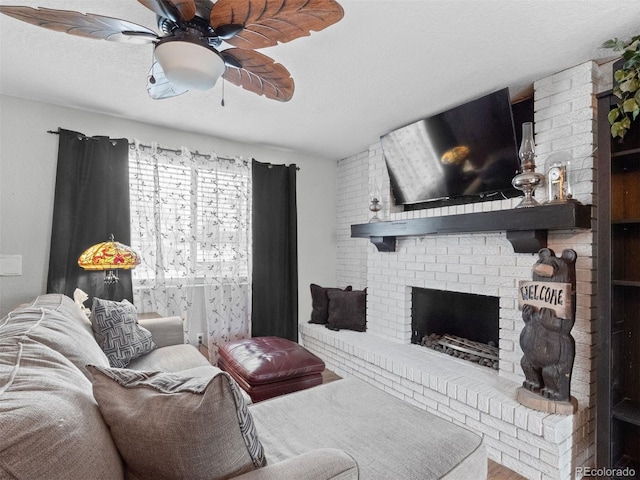 living area featuring a textured ceiling, a brick fireplace, and a ceiling fan