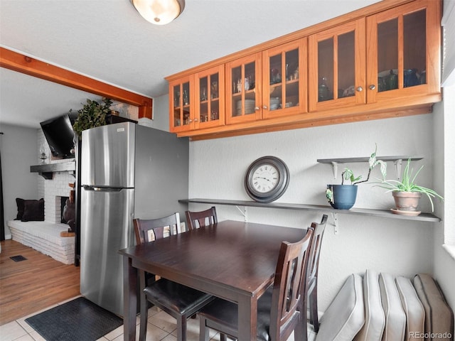 dining room featuring a brick fireplace, visible vents, and tile patterned floors