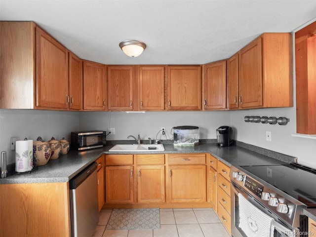 kitchen with light tile patterned floors, appliances with stainless steel finishes, brown cabinetry, and a sink