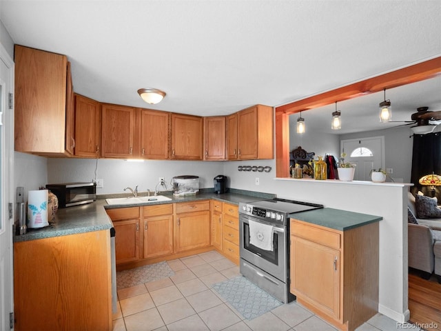 kitchen with stainless steel appliances, dark countertops, a sink, and a peninsula