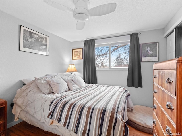 bedroom with a textured ceiling, a ceiling fan, and wood finished floors