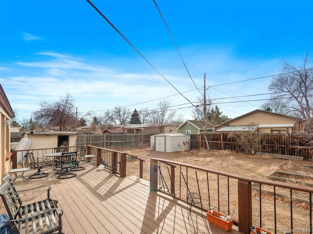 deck featuring a shed, outdoor dining area, an outdoor structure, and a fenced backyard