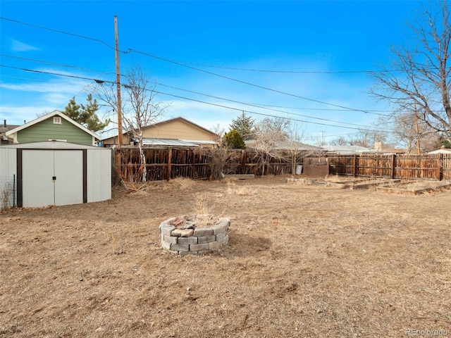 view of yard with an outbuilding, a fenced backyard, a fire pit, and a storage unit