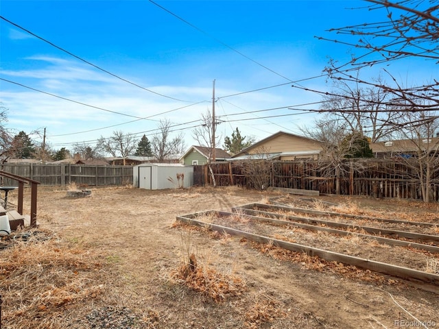 view of yard with an outbuilding, a storage unit, a fenced backyard, and a vegetable garden