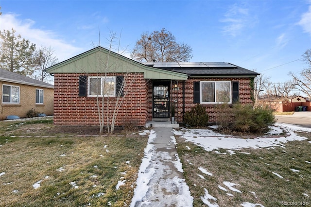 bungalow-style house with a lawn and solar panels