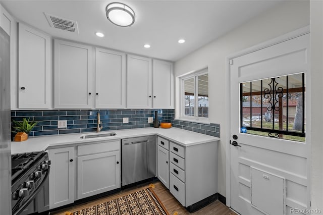 kitchen featuring dishwasher, black gas range oven, a wealth of natural light, sink, and white cabinetry