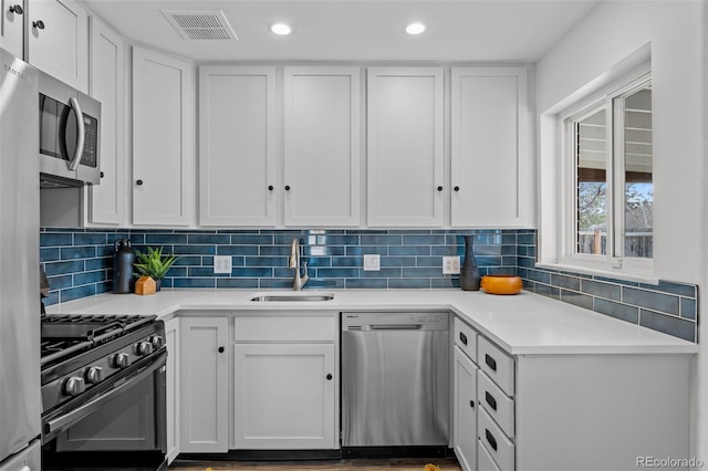 kitchen with appliances with stainless steel finishes, tasteful backsplash, white cabinets, and sink