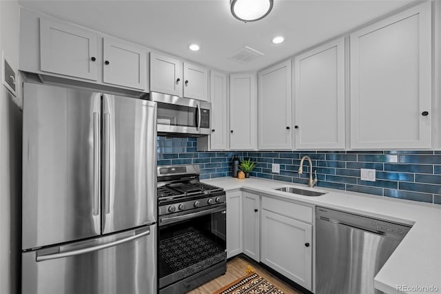 kitchen with sink, appliances with stainless steel finishes, tasteful backsplash, and white cabinetry