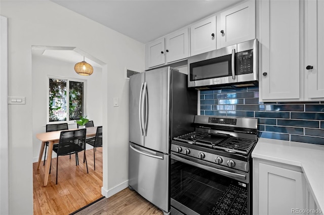 kitchen featuring light hardwood / wood-style flooring, stainless steel appliances, white cabinetry, and tasteful backsplash