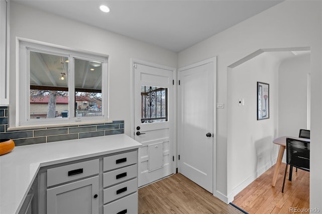 kitchen featuring gray cabinetry, light wood-type flooring, and backsplash