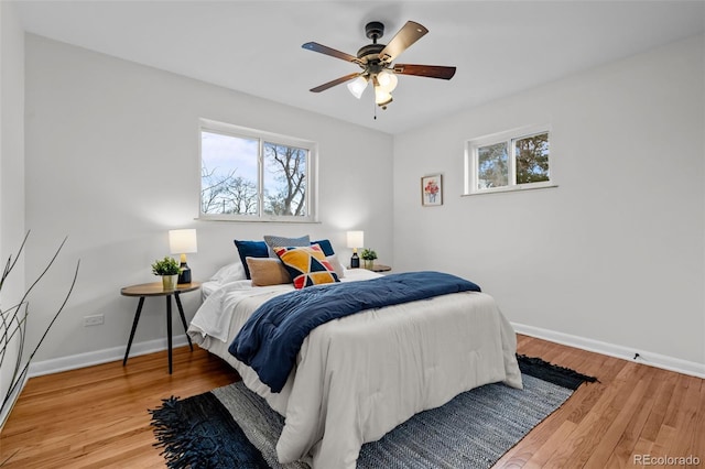 bedroom with wood-type flooring, multiple windows, and ceiling fan