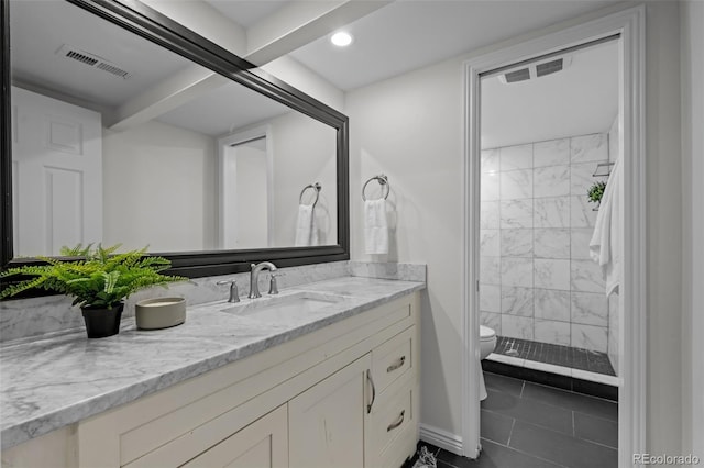 bathroom featuring tiled shower, tile patterned flooring, vanity, and toilet