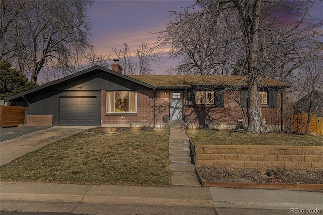 view of front of property featuring driveway, a garage, a chimney, a front lawn, and brick siding