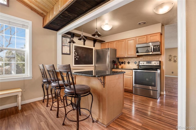 kitchen with tasteful backsplash, visible vents, a breakfast bar, light brown cabinetry, and stainless steel appliances