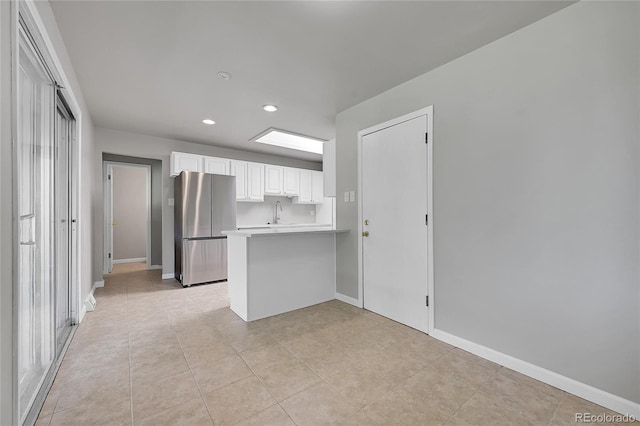 426 Kenton St, Aurora, CO 80010 - kitchen featuring freestanding refrigerator, a peninsula, recessed lighting, white cabinets, and light countertops