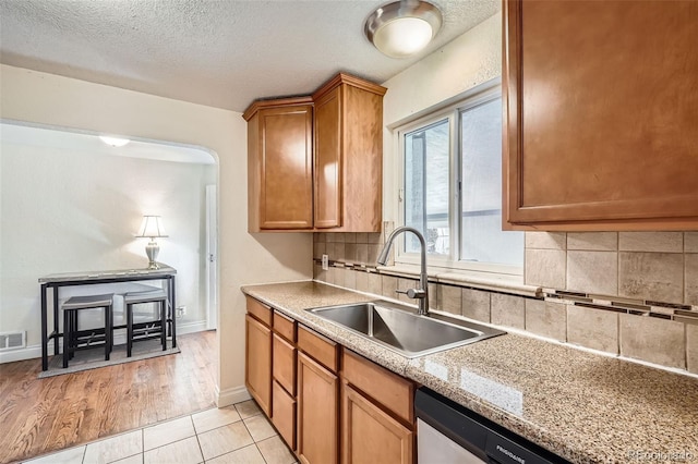 kitchen featuring tasteful backsplash, sink, light tile patterned floors, and a textured ceiling